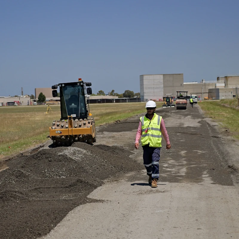 Eifers crew member walking the maintenance road site with CAT equipment behind