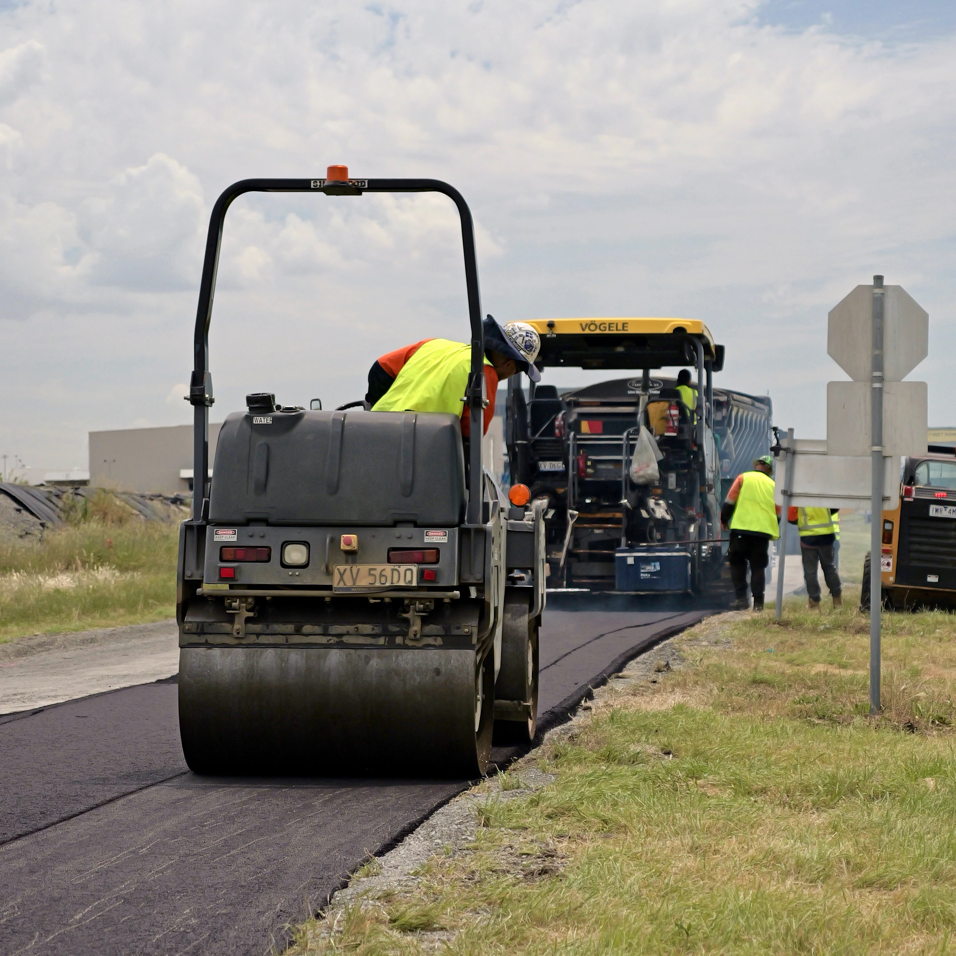 Road roller compacting fresh Greenpave asphalt with Vögele paver behind